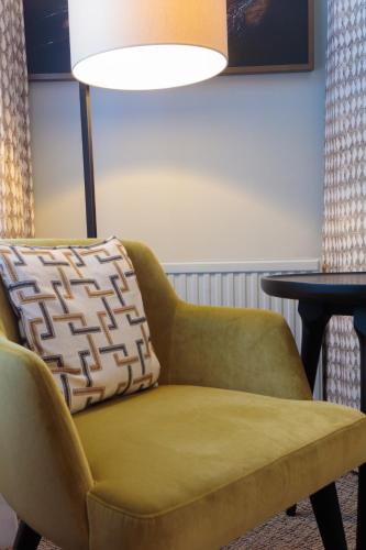 a green chair with a pillow sitting next to a table at Mercure Blackburn Dunkenhalgh Hotel & Spa in Blackburn