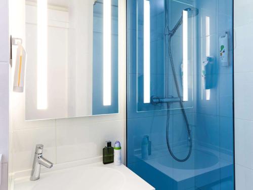 baño con ducha y puerta de cristal azul en ibis Styles Toulouse Nord Sesquieres, en Toulouse