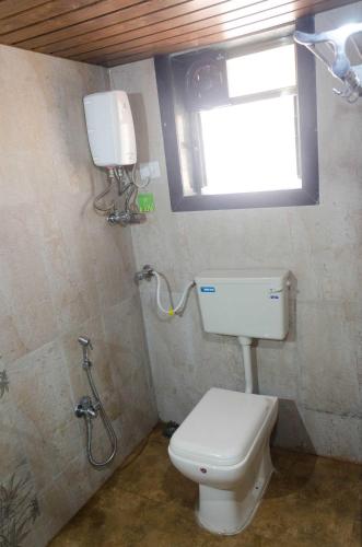 a small bathroom with a toilet and a window at Malhar Villa -Kashid in Kashid