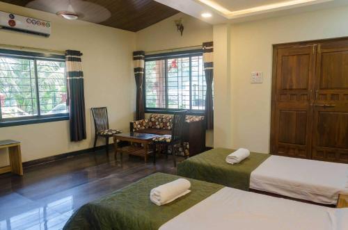 a hotel room with two beds and a table and chairs at Malhar Villa -Kashid in Kashid