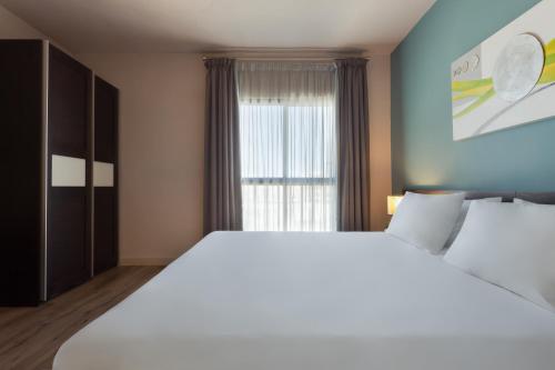 uma grande cama branca num quarto com uma janela em Hotel Argento em St. Julian's