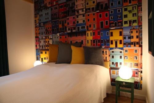 a bedroom with a white bed with a colorful wall at Döme's Point in Leányfalu