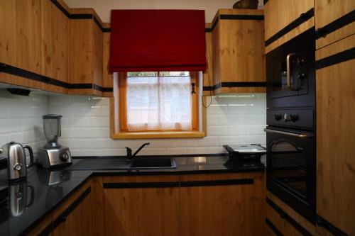 a kitchen with wooden cabinets and a red window at Döme's Point in Leányfalu