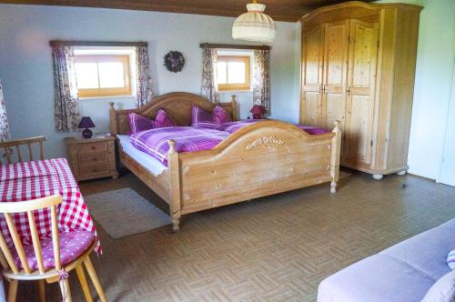 a bedroom with a large wooden bed with purple sheets at Mayerhof in Pittenhart
