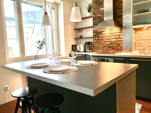 a kitchen with a table with plates and wine glasses at City Home Finland Ratina - Spacious Studio with Own SAUNA and Great Location Next to Uros Live Arena in Tampere