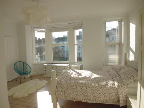 a bedroom with a bed and a chair and windows at Stunning townhouse at Plymouth Hoe in Plymouth