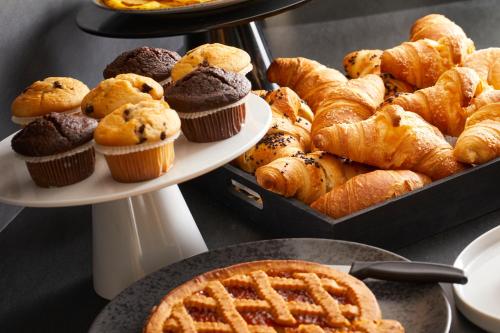 a bunch of pastries and muffins on two plates at Nodo Hotel in Codroipo