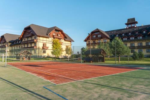a tennis court in front of some large buildings at TATRYSTAY Apartment C3 in Veľká Lomnica
