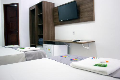 a room with three beds and a flat screen tv at Pousada Arco Iris Fortaleza in Fortaleza