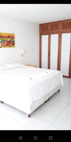 a bedroom with a white bed with a painting on the wall at Casa Quinta Melgar in Melgar