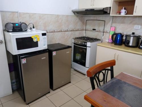 a kitchen with a microwave and a stove and a table at Habitación RRB in Lima