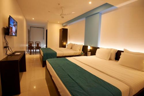 a hotel room with two beds and a flat screen tv at HOTEL CITY POINT in Shirdi