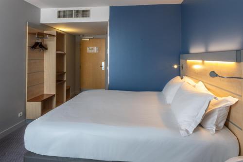 a bedroom with a large white bed with a blue wall at Holiday Inn Express Saint-Nazaire by IHG in Saint-Nazaire