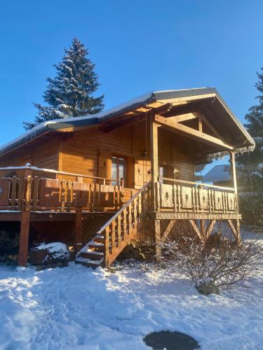 a log cabin in the snow with a porch and stairs at Chalet des Moineaux in Saint-Laurent-en-Grandvaux