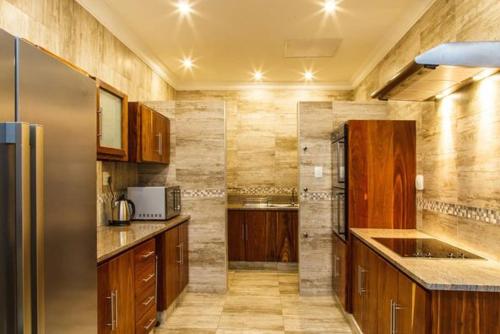 a kitchen with wooden cabinets and a stainless steel refrigerator at Blyde Canyon, A Forever Resort in Matibidi