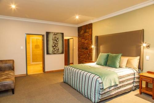 a bedroom with a large bed and a chair at Blyde Canyon, A Forever Resort in Matibidi