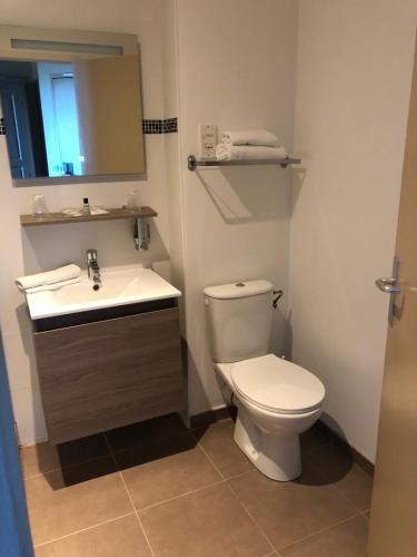 ein Badezimmer mit einem WC, einem Waschbecken und einem Spiegel in der Unterkunft The Originals City, Hôtel La Cour Carrée, EU in Eu
