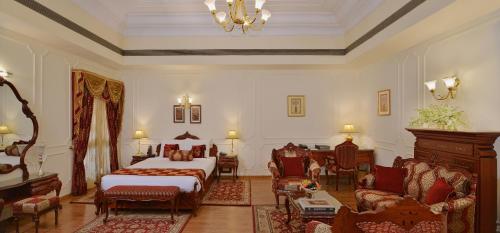 a bedroom with a bed and a couch and chairs at Noor-Us-Sabah Palace in Bhopal