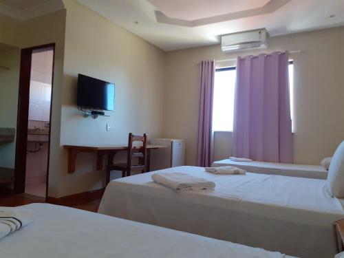 a hotel room with two beds and a television at Hotel Litoral in Aracaju