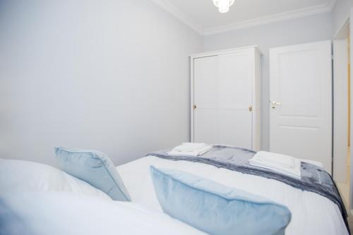 a white bed with blue pillows and a mirror at Hamptons Apartment in Świnoujście