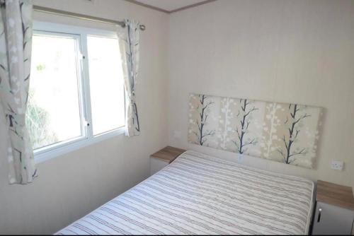 een slaapkamer met een bed en een raam bij Comfortable 3-Bed Caravan - Combe Haven in Hollington
