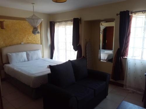 een slaapkamer met een bed, een bank en een spiegel bij Kim Suites - Mvuli Studio Apartment in Nairobi