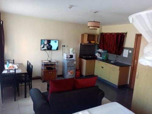 een woonkamer met een bank en een keuken met een tafel bij Kim Suites - Mvuli Studio Apartment in Nairobi