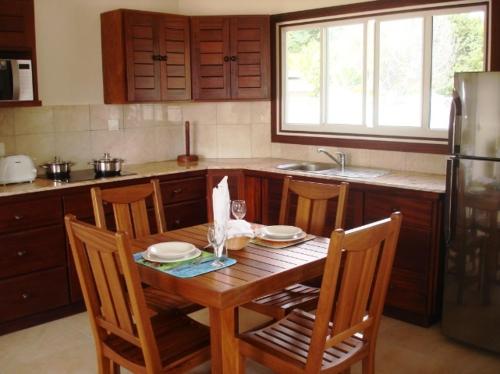 a kitchen with a wooden table with chairs and a refrigerator at Cote d'Or Footprints in Baie Sainte Anne