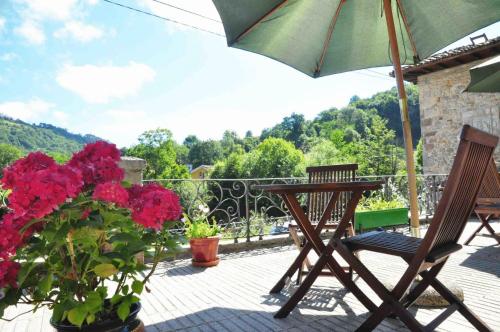 a patio with two chairs and an umbrella and flowers at Hotel La Balsa in Cangas de Onís