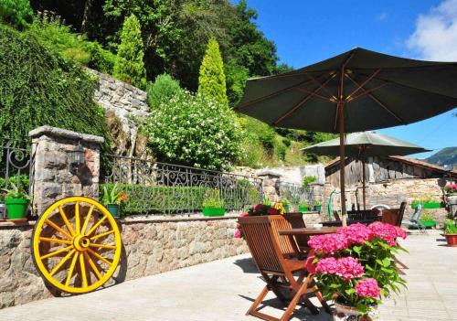 a patio with an umbrella and a table with flowers at Hotel La Balsa in Cangas de Onís