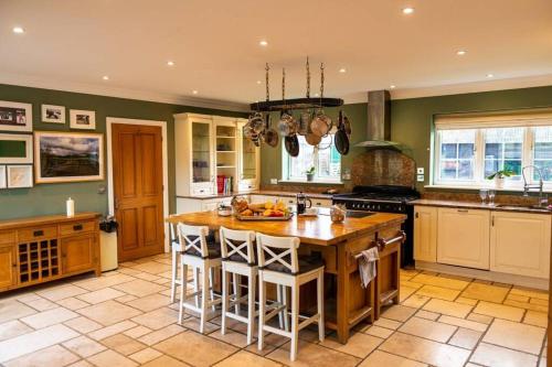 a kitchen with a large island in a kitchen at Langford farmhouse - New Forest National Park Luxury 4bd, hot tub, cinema, 10 acres in Bartley