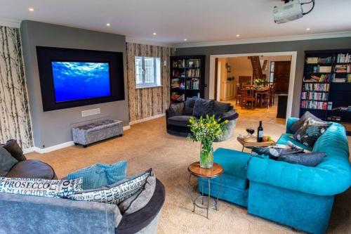 a living room with blue couches and a flat screen tv at Langford farmhouse - New Forest National Park Luxury 4bd, hot tub, cinema, 10 acres in Bartley