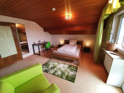 a bedroom with a bed and a desk and a green couch at Gästehaus Aurelia in Wiesau