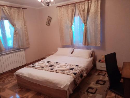 a bedroom with a bed with white sheets and windows at Casa Dana in Borsa