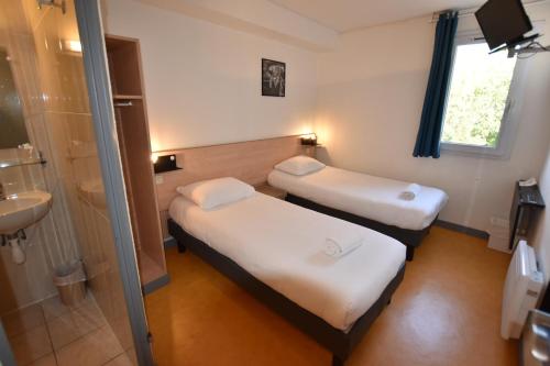 two beds in a room with a sink and a shower at Face West Le Pontet in Le Pontet