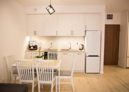 een keuken met een tafel en een witte koelkast bij Apartament Royal Place I Jurowiecka 17 in Białystok