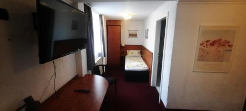 einen Flur mit einem Zimmer mit einem Bett und einem TV in der Unterkunft Hotel Corveyer Hof in Höxter