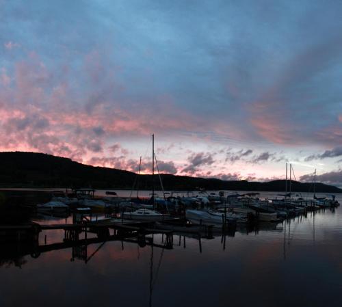 a group of boats docked at a marina at sunset at Lake Front Hotel in Cooperstown