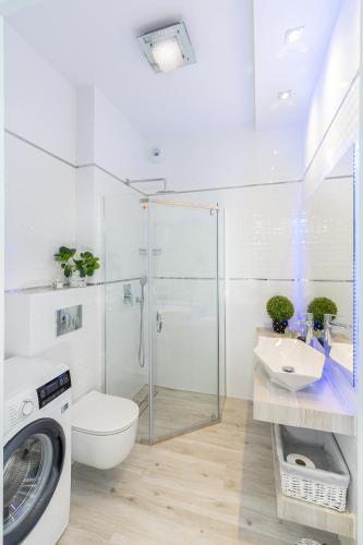 a white bathroom with a washing machine and a sink at Angel Apartments 2 in Krakow