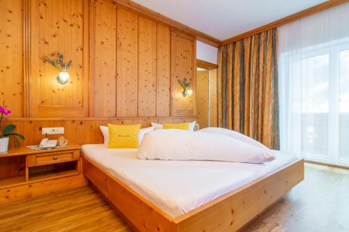 sypialnia z dużym łóżkiem w drewnianej ścianie w obiekcie Pension am Rain w Neustift im Stubaital