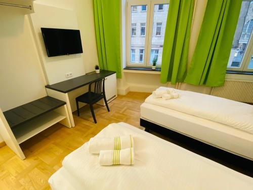 a room with two beds and a desk with a television at bestprice Hotel Aachen Hauptbahnhof in Aachen
