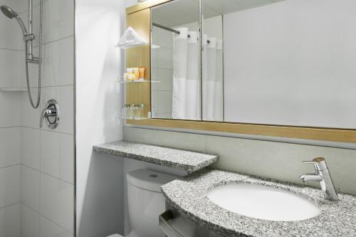 La salle de bains est pourvue d'un lavabo, d'un miroir et de toilettes. dans l'établissement Club Quarters Hotel World Trade Center, New York, à New York