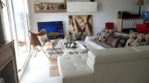 3 bedrooms appartement with sea view furnished terrace and wifi at Nigran في نيغران: غرفة معيشة مع أريكة بيضاء وتلفزيون