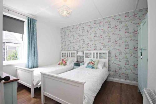 a bedroom with two beds and a wall covered in flowers at Charming 2-Bed Cottage in the heart of Stanhope in Bishop Auckland