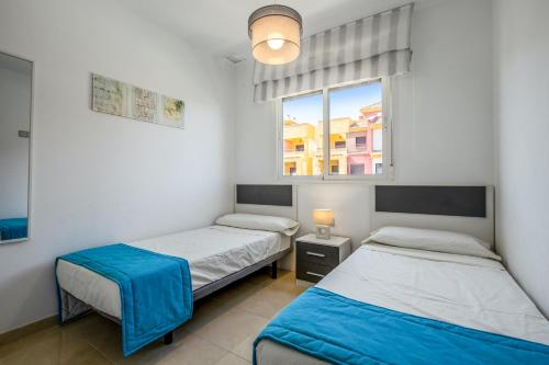 two beds in a room with a window at Spacious Apartment in Orihuela with Sea View in Playas de Orihuela