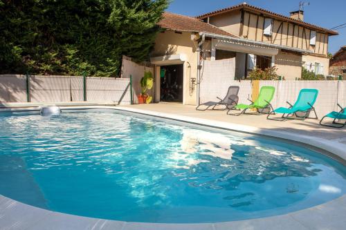 une piscine avec des chaises et une maison dans l'établissement Villa charmante en pleine campagne de Courrensan avec piscine privée, à Courrensan