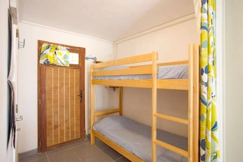 Pokój z łóżkiem piętrowym z 2 łóżkami piętrowymi i drzwiami w obiekcie Studio a Bormes les Mimosas a 400 m de la plage avec jardin clos et wifi w mieście Bormes-les-Mimosas