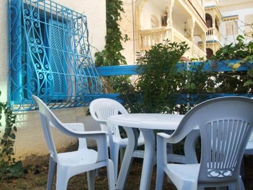 een witte tafel en stoelen voor een gebouw bij One bedroom appartement at Akouda 200 m away from the beach with shared pool and enclosed garden in Port El Kantaoui