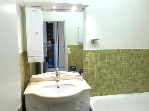 une personne prenant une photo d'une salle de bains avec lavabo dans l'établissement Appartement confortable avec vue sur la mer - Neufchâtel-Hardelot, à Neufchâtel-Hardelot