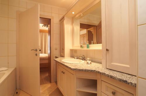 a bathroom with a sink and a mirror and a tub at Landhotel Strasserwirt in Sankt Ulrich am Pillersee